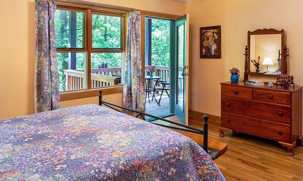 A bedroom at the Luhn House with doors to the deck