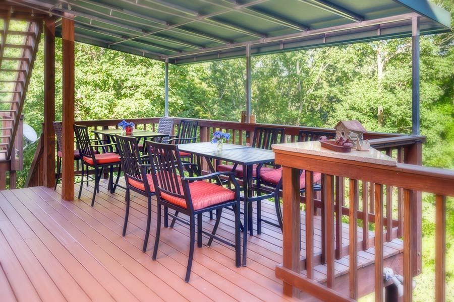 The covered porch at Bent Creek Lodge, set for outdoor dining above the gardens
